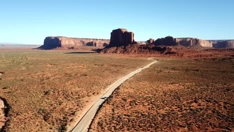 Toma-Aérea-De-Un-Automóvil-Conduciendo-Hacia-Monument-Valley,-Un-Paisaje-Impresionante-En-EE.UU.