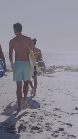 animación de la bandera estadounidense sobre un grupo diverso de amigos caminando con tablas de surf en la playa