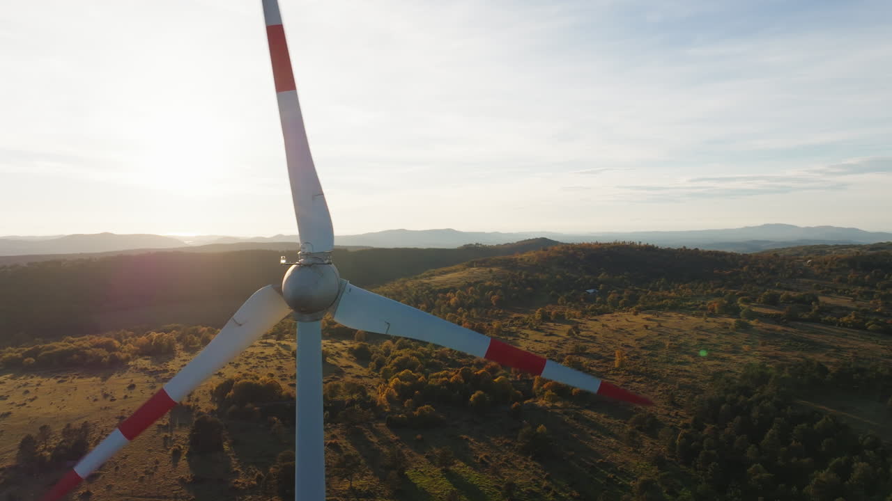 Un drone cattura una turbina eolica al tramonto, evidenziando l'energia rinnovabile e la tecnologia pulita in un