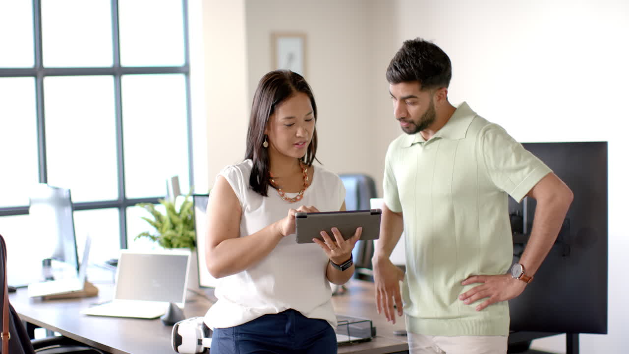 Discussing project, colleagues using tablet in modern office with robotic equipment