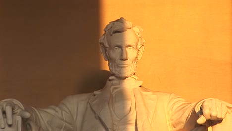 president lincoln's sculpted face is seen half in shadow the other half bathed in golden light