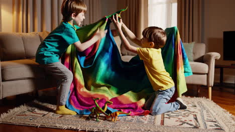 two young boys building a colorful blanket fort in the living room