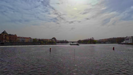 From-afar,-Vlatva-River's-shores-show-bridges,-buildings-and-university,-creating-a-pretty-view