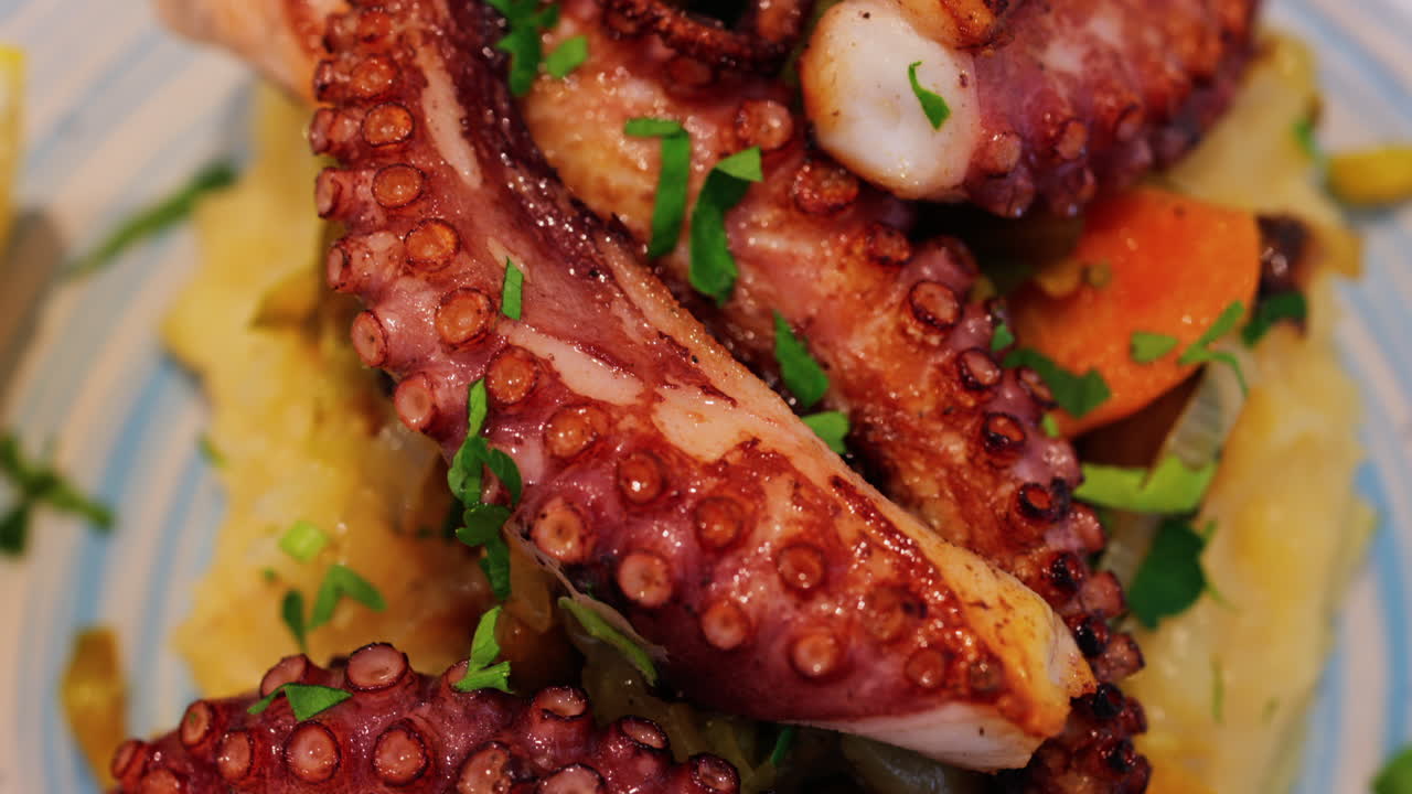Close up of grilled octopus on a puree and a piece of lemon at a restaurant
