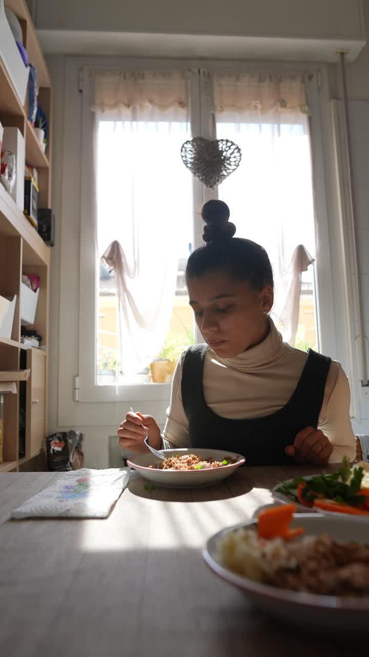 una mujer joven almorzando en casa.