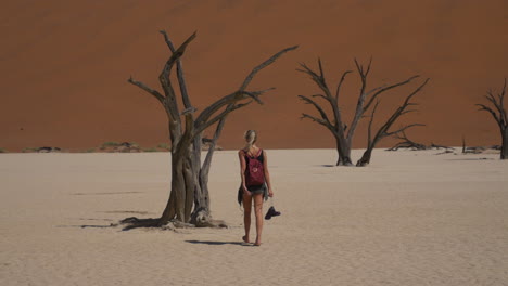 girl walking barefoot in desert with shoes in her hand