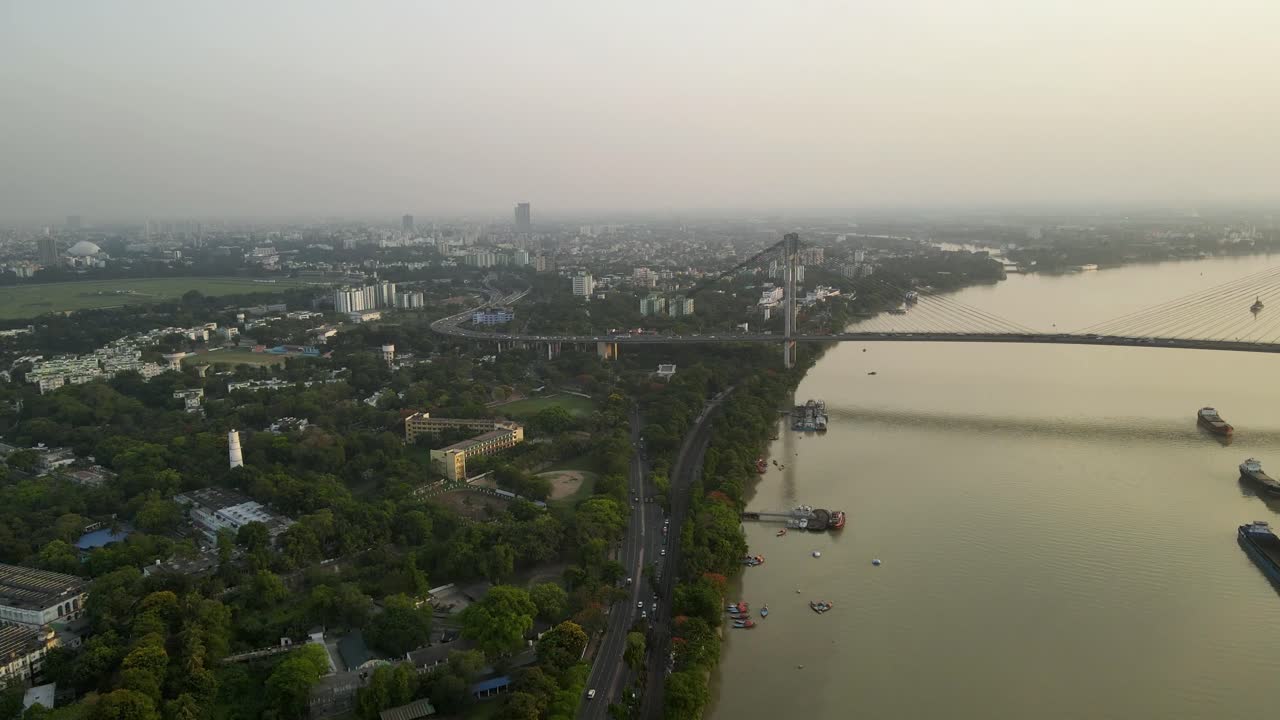 Aerial drone capture of Vidyasagar Bridge during sunset, city lights twinkling over the tranquil river.