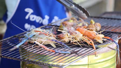person grilling shrimp over charcoal flames