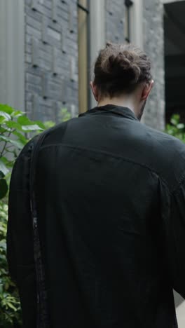 man with a top knot near a brick building