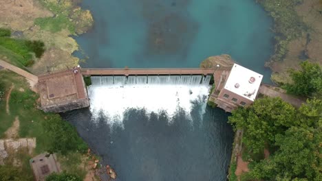 skyview of a rushing water thru a dam from drone angle looking down from very high