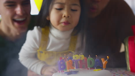 Nahaufnahme-Einer-Familie-Mit-Zwei-Vätern,-Die-Zu-Hause-Den-Geburtstag-Ihrer-Tochter-Feiern-Und-Kerzen-Auf-Dem-Kuchen-Ausblasen