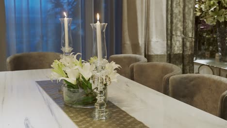 luxurious dining table setup with white lilies and candles in glass candelabra