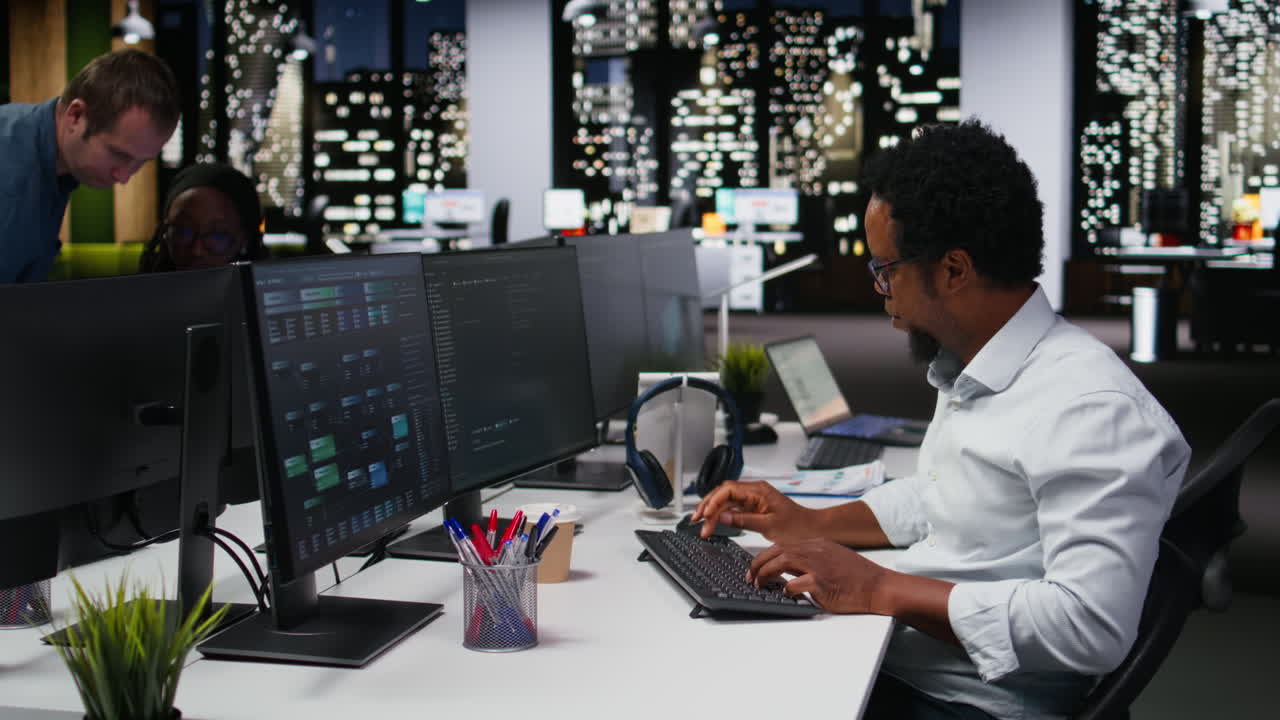 African American Programmer Working on Multiple Computer Screens in Modern Office