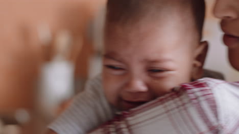 unhappy baby crying on mothers shoulder upset infant screaming with young mom calming tired child