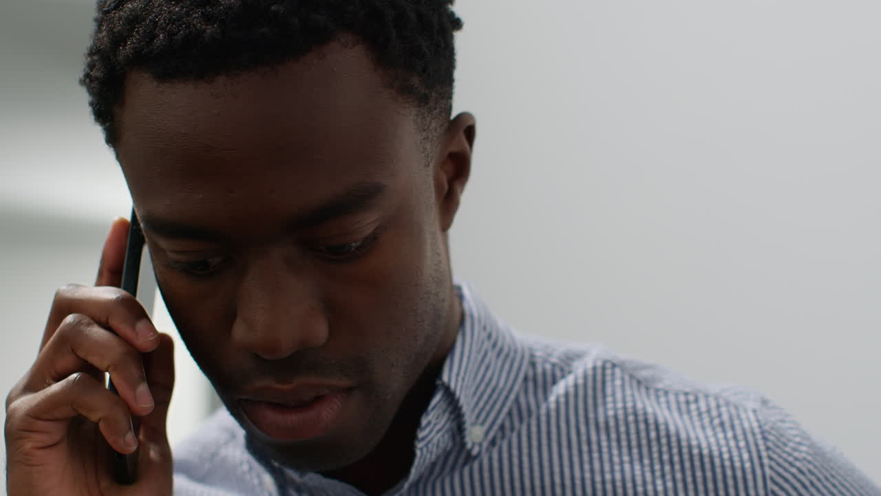 Close Up Of Young Businessman In Office Talking On Mobile Phone Reacting To Bad News Looking Unhappy And Depressed
