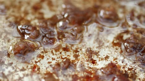 primer plano de una sartén sucia y grasa con aceite y residuos de alimentos