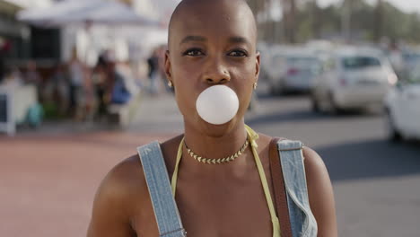 retrato de una feliz mujer afroamericana soplando chicle sonriendo alegremente disfrutando de las vacaciones de verano en una cálida y soleada calle frente a la playa serie de personas reales