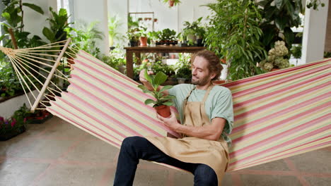 man relaxing in a hammock in a plant shop holding a plant