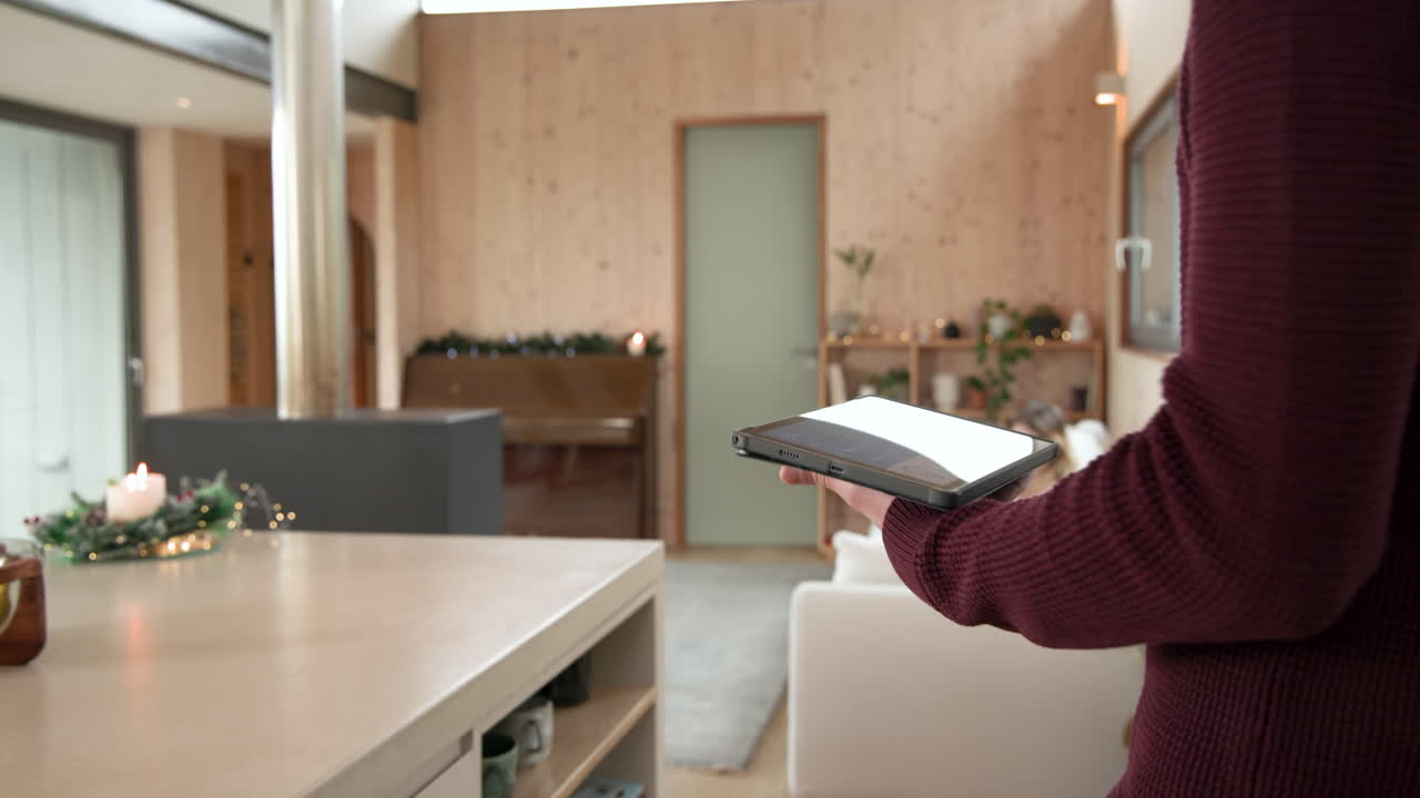 Using tablet to control smart home in cozy Christmas living room, copy space