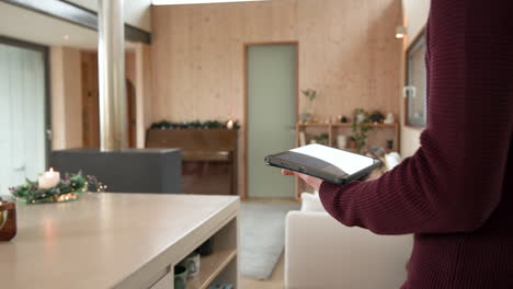using tablet to control smart home in cozy christmas living room, copy space