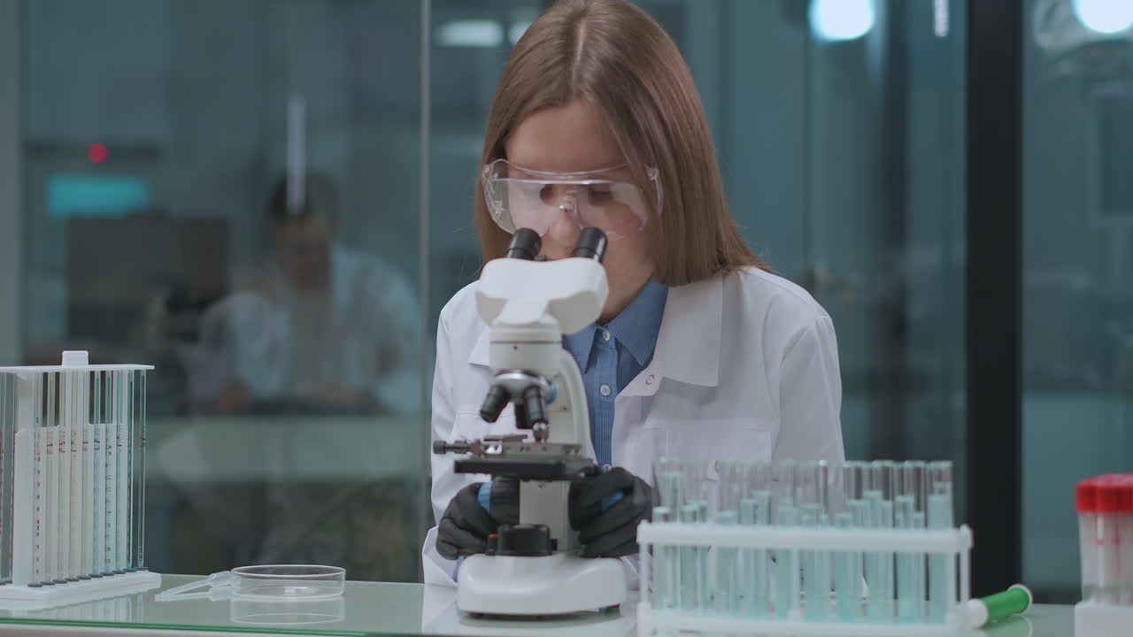 microbiologist woman is exploring sample in laboratory looking into microscope specialist of DNA analysis medical lab in university of virology