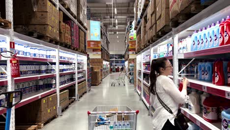 Woman-is-choosing-her-fabric-softener-in-the-cleaning-aisle,-smelling-the-different-scents