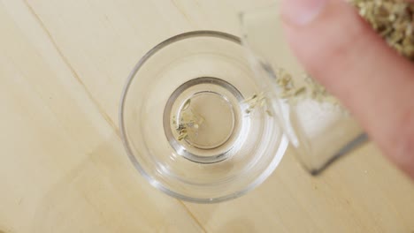 slow motion of dried oregano being poured into a glass bowl from above