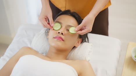 woman receiving a facial spa treatment with cucumber masks