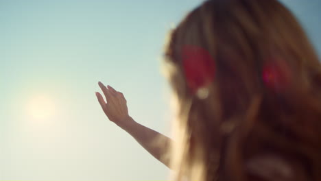 Cerrar-El-Rayo-De-Sol-A-Través-De-Los-Dedos-De-La-Mujer.-Mujer-De-Espaldas-Con-La-Mano-Tocando-El-Sol.