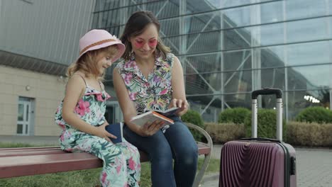 mother and daughter near airport. woman hold passports and tickets in hand. child and mom vacation