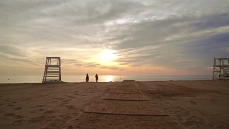 Bei-Sonnenuntergang-Am-Strand-Spazieren-Gehen.-Gruppe-Von-Freunden,-Die-Sich-Am-Strand-Ausruhen