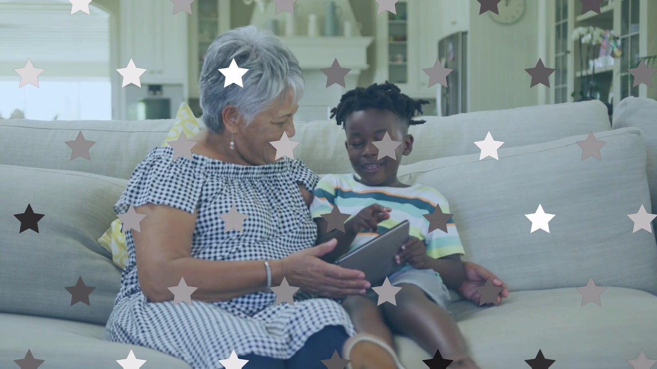 Gran holding tablet at grandson level on sofa, child tapping and swiping, star overlay for learning