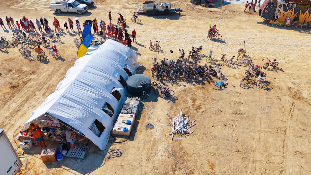 Nevada, USA, 22 August 2025: Line of people and bicycles at Burning Man camp. Group of people with bicycles forming a line near tents and trucks in Burning Man desert camp