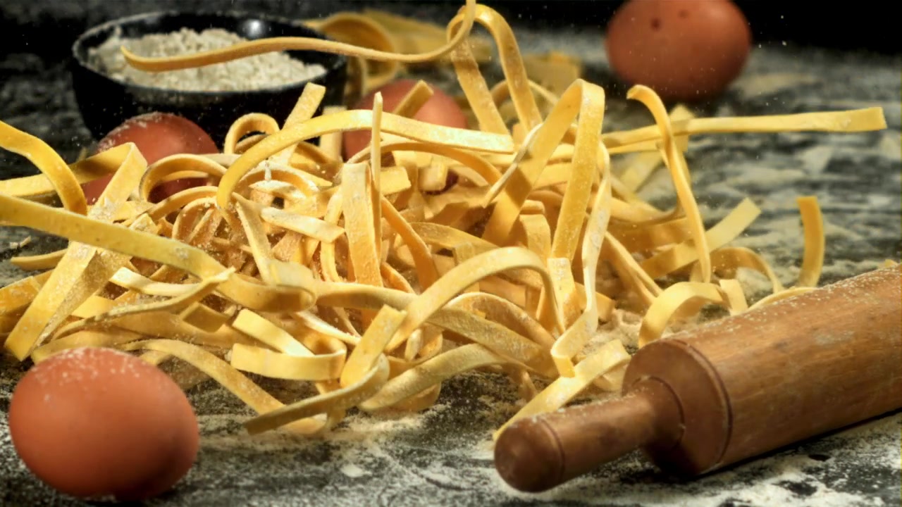 Movimento rallentato di tagliatelle fresche che cadono con farina e uova