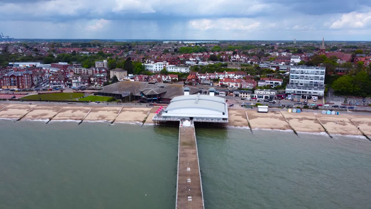 Pier and Beachfront; a revealing aerial footage of a pier and a town, communities and houses, cars moving and parking areas, birds flying below, lovely rainclouds plus rain falling in the horizon