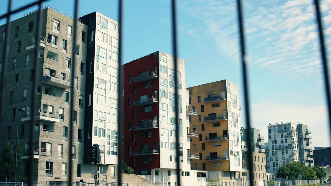 Modernos edificios de apartamentos residenciales en Nantes, Francia, vistos a través de una valla difuminada. Desarrollo urbano con arquitectura contemporánea colorida y bienes inmuebles de viviendas con un cielo azul de fondo.