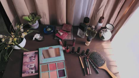 polvo de maquillaje de belleza, esmalte de uñas y cepillo para el cabello en el tocador junto a la cortina