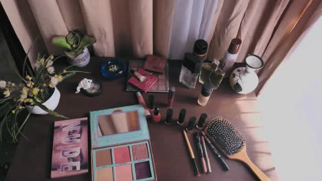 beauty make up powder, nail polish and hair brush on dresser table beside curtain