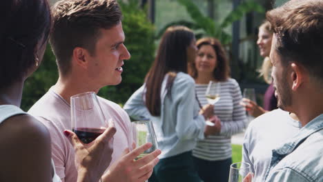 group of multi-cultural friends relaxing and drinking wine in garden together