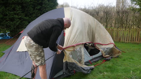 a man erecting a tent threading a tent pole on a campsite whilst camping