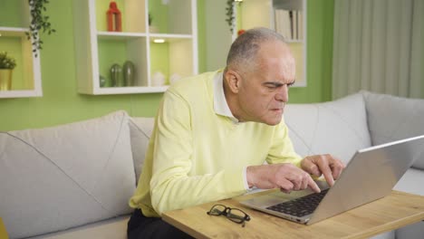 Elderly-retired-man-using-laptop-at-home,-wearing-his-glasses.