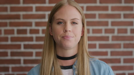 retrato joven hermosa mujer rubia estudiante buscando serio calma caucásica mujer cámara lenta en la pared de ladrillo fondo fondo