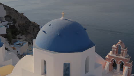 Iconic-blue-church-dome-and-pink-church-bell-in-Oia,-Santorini