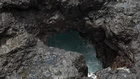 volcanic rock hole with sea water waves splashing into it, close up, tenerife