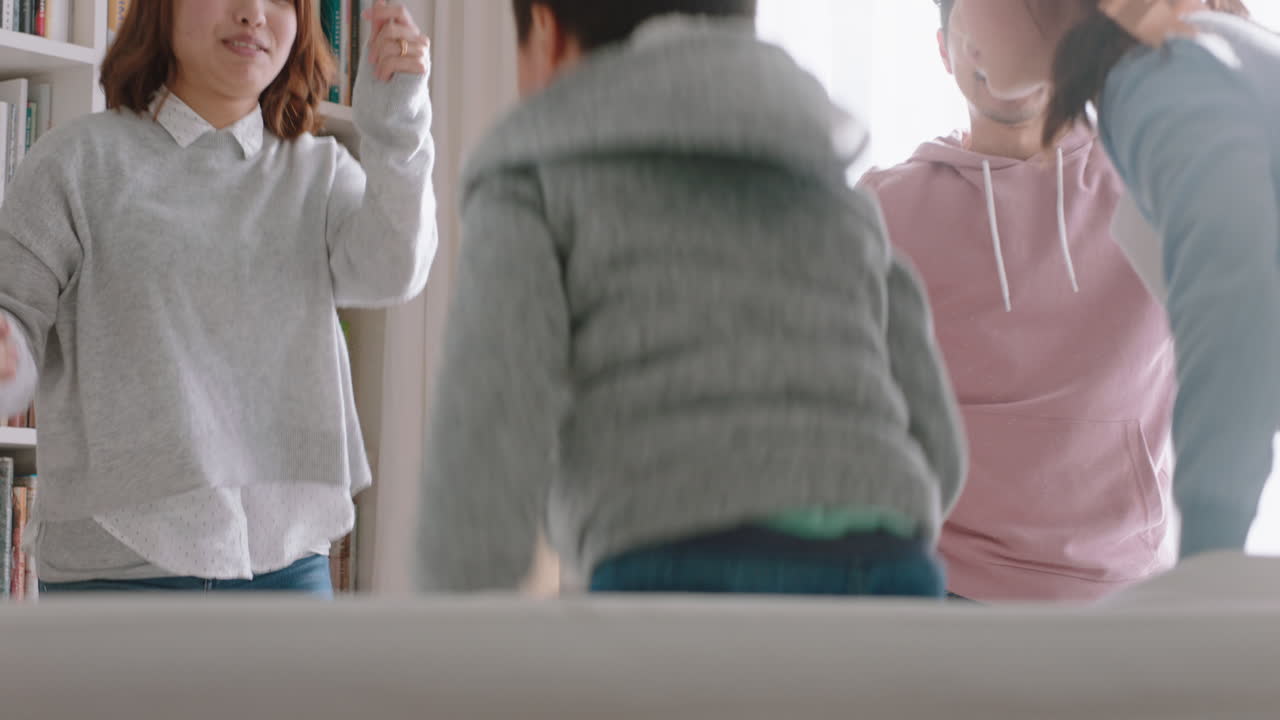 행복한 아시아 가족이 집에서 춤을 추고 즐거운 춤을 추고 함께 축하합니다. 작은 아이들이 엄마와 아빠와 함께 축하하고 흥미진진한 주말 4k 영상을 즐기고 있습니다.