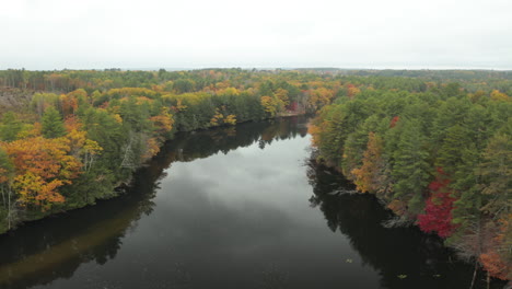 Aerial-shot-of-calm-river-winding-in-North-American-autumn-forest