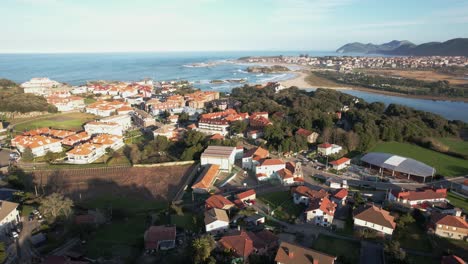 Vista-Aérea-De-Isla,-Un-Pequeño-Pueblo-En-La-Ciudad-De-Cantabria-Y-En-El-Fondo-Noja-Y-Enormes-Olas