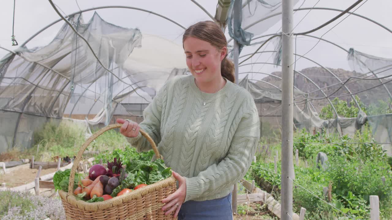 портрет улыбающейся кавказской женщины с корзиной с овощами в теплице