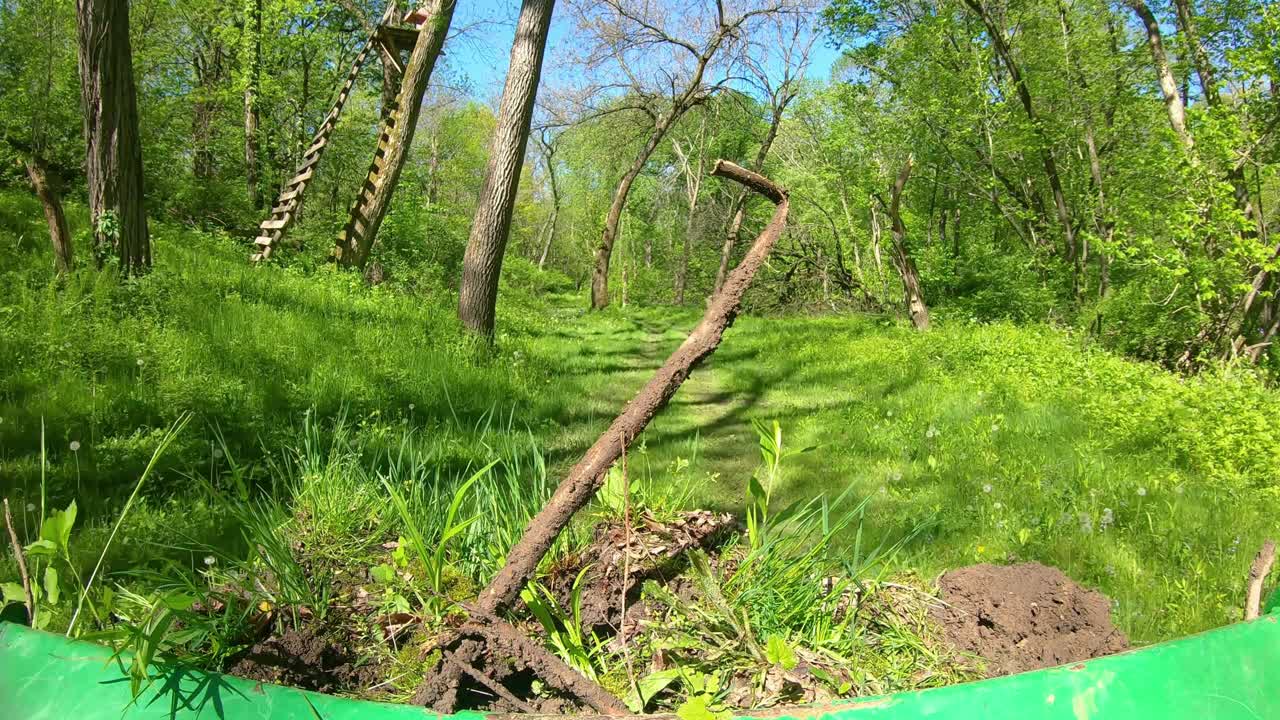 숲이 우거진 지역에서 작은 녹색 트랙터를 운영하는 pov