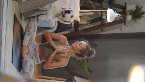 woman meditating at home with her dog